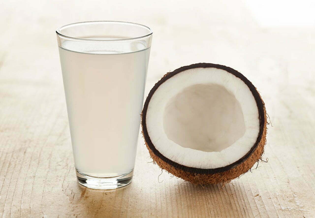 One broken coconut and a glass of coconut water